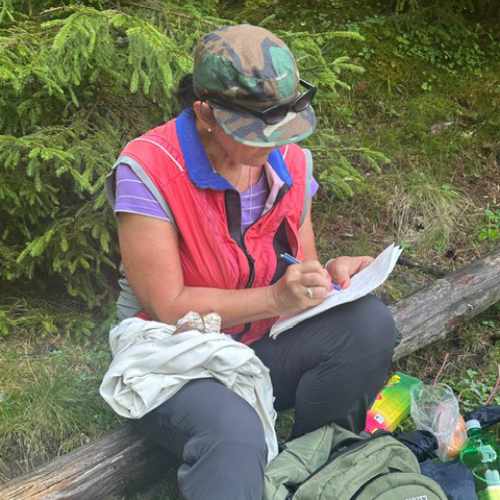 Barbara macht pause beim Wandern und schreibt in ein Heft