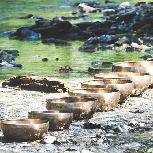 Klangschalen aufgereiht an einem Seeufer